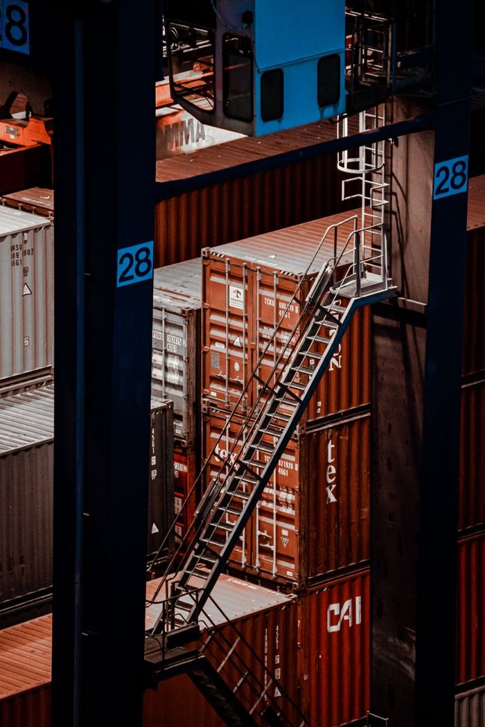 our-story Elevated view of cargo containers with a metal staircase at a shipping facility.