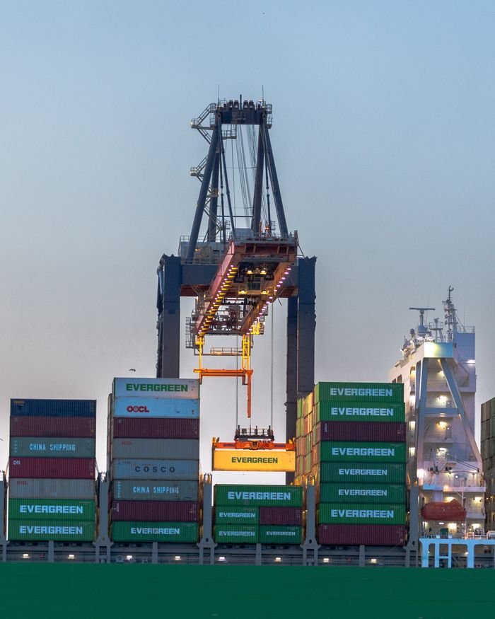 services-04 A busy container crane in Rotterdam port handling international cargo operations at dusk.
