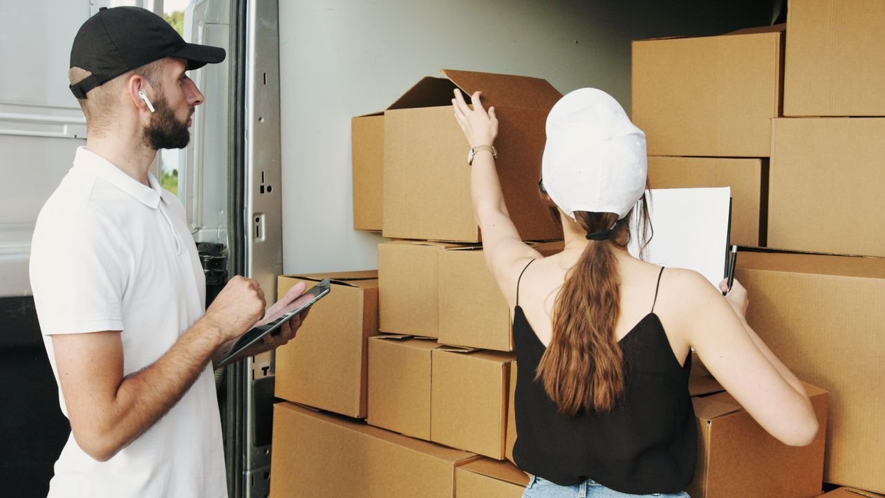 services-03 Two couriers organizing boxes in a delivery van, checking inventory.